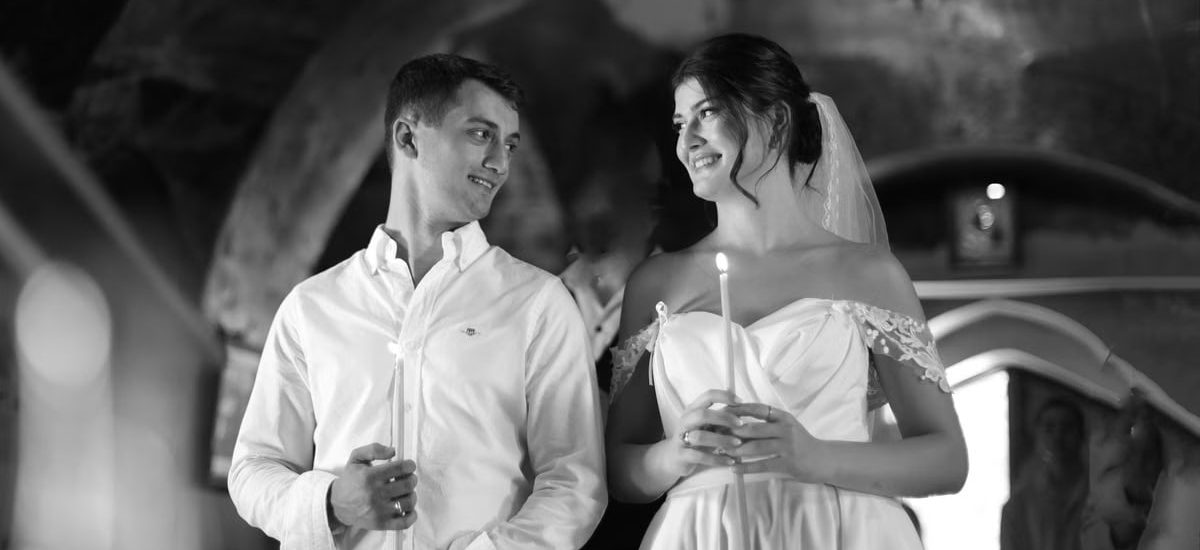 A bride and groom holding candles in a traditional romantic wedding ceremony setting.