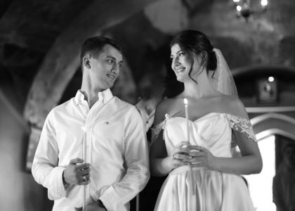 A bride and groom holding candles in a traditional romantic wedding ceremony setting.